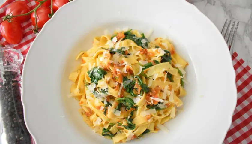 Pyszne tagliatelle ze szpinakiem i pomidorami, posypane parmezanem. Idealne danie na szybki obiad.