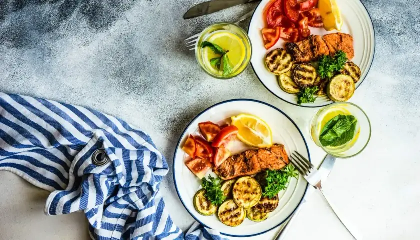 Dwa talerze z łososiem, grillowaną cukinią i pomidorami. Idealne danie na dieta niskowęglowodanowa.